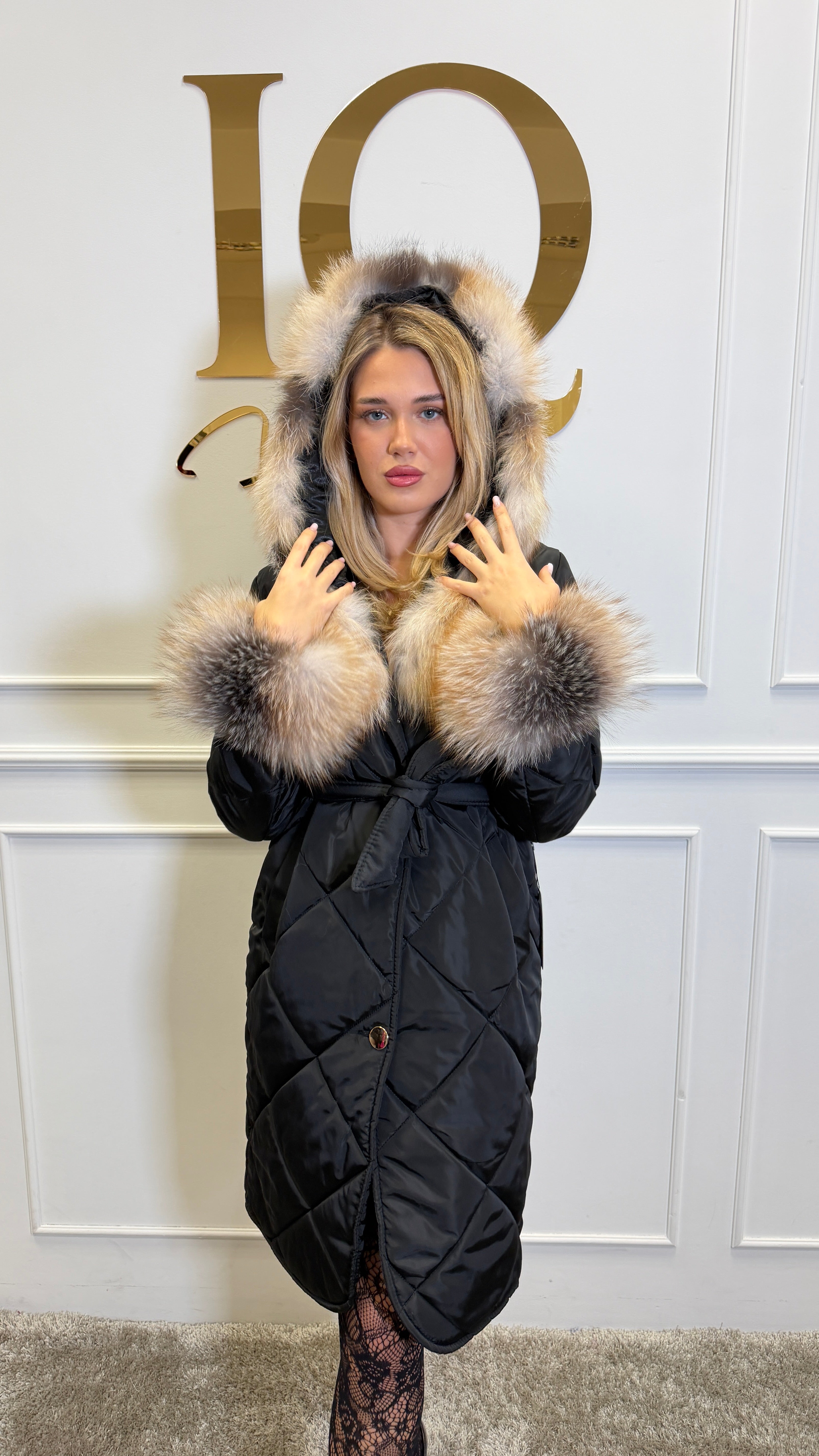 Black and gold faux fur coat with natural fur accents from ELVE STYLE SRL, stylishly displayed on a hanger.